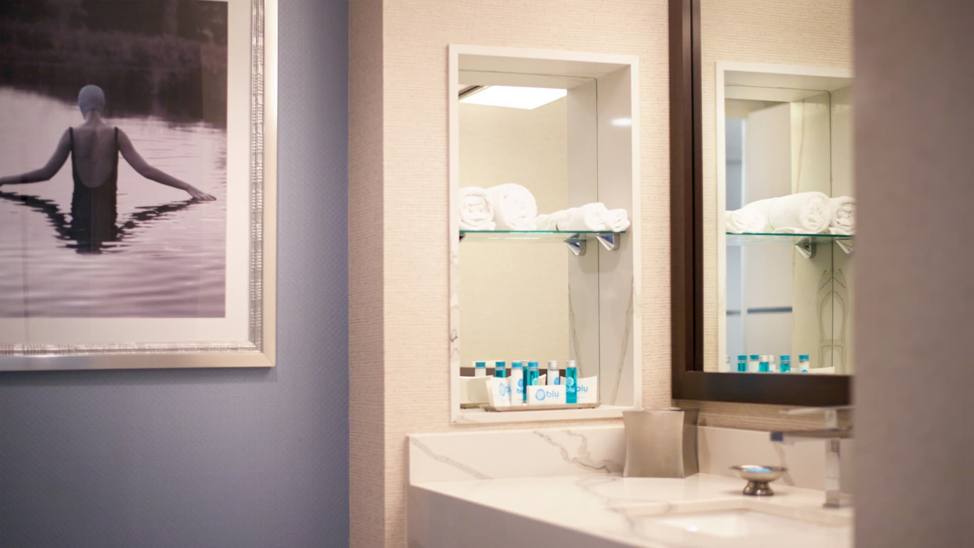 a bathroom sink with a mirror and a picture on the wall