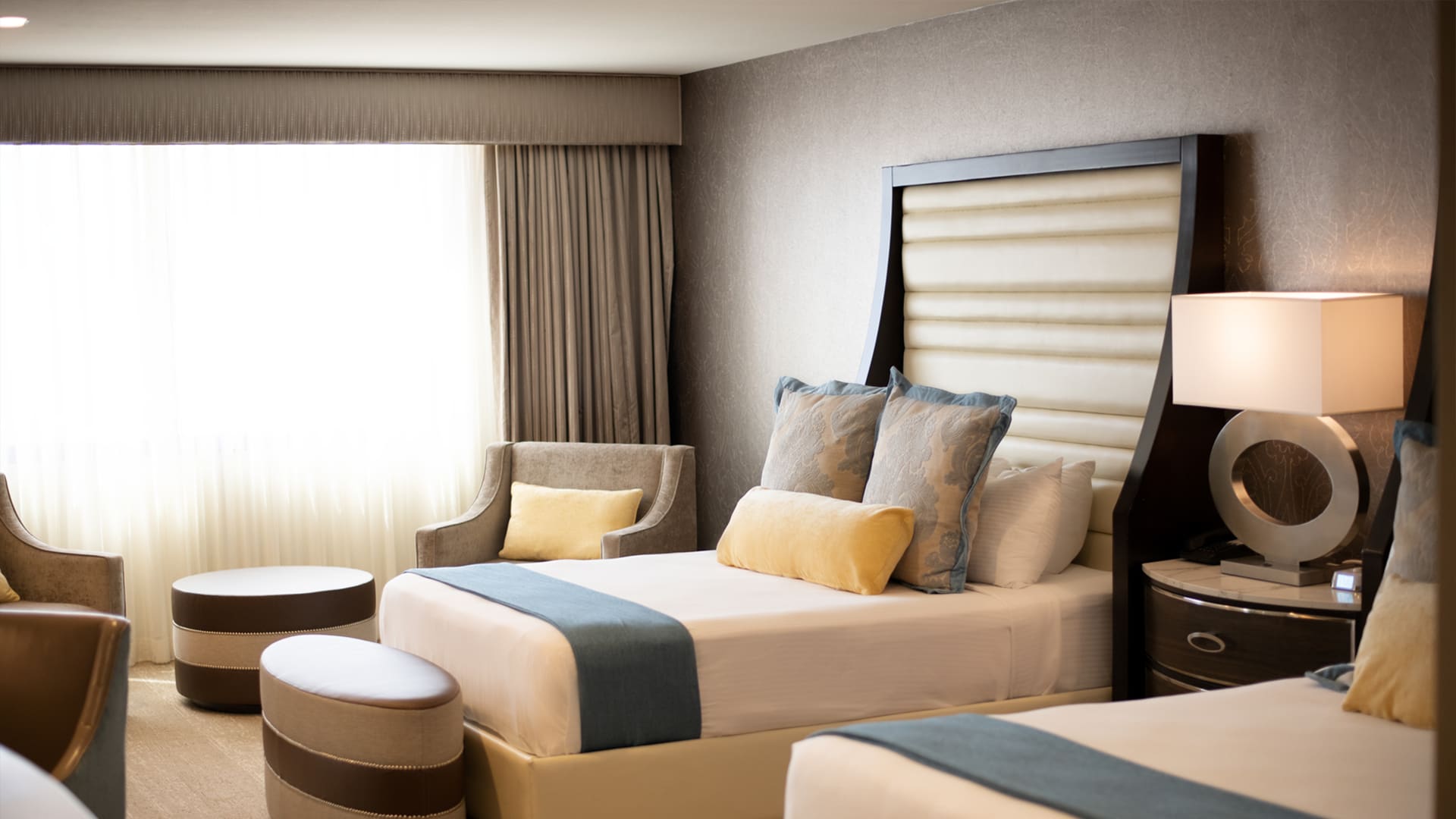 A hotel room with two beds, a chair, and a window