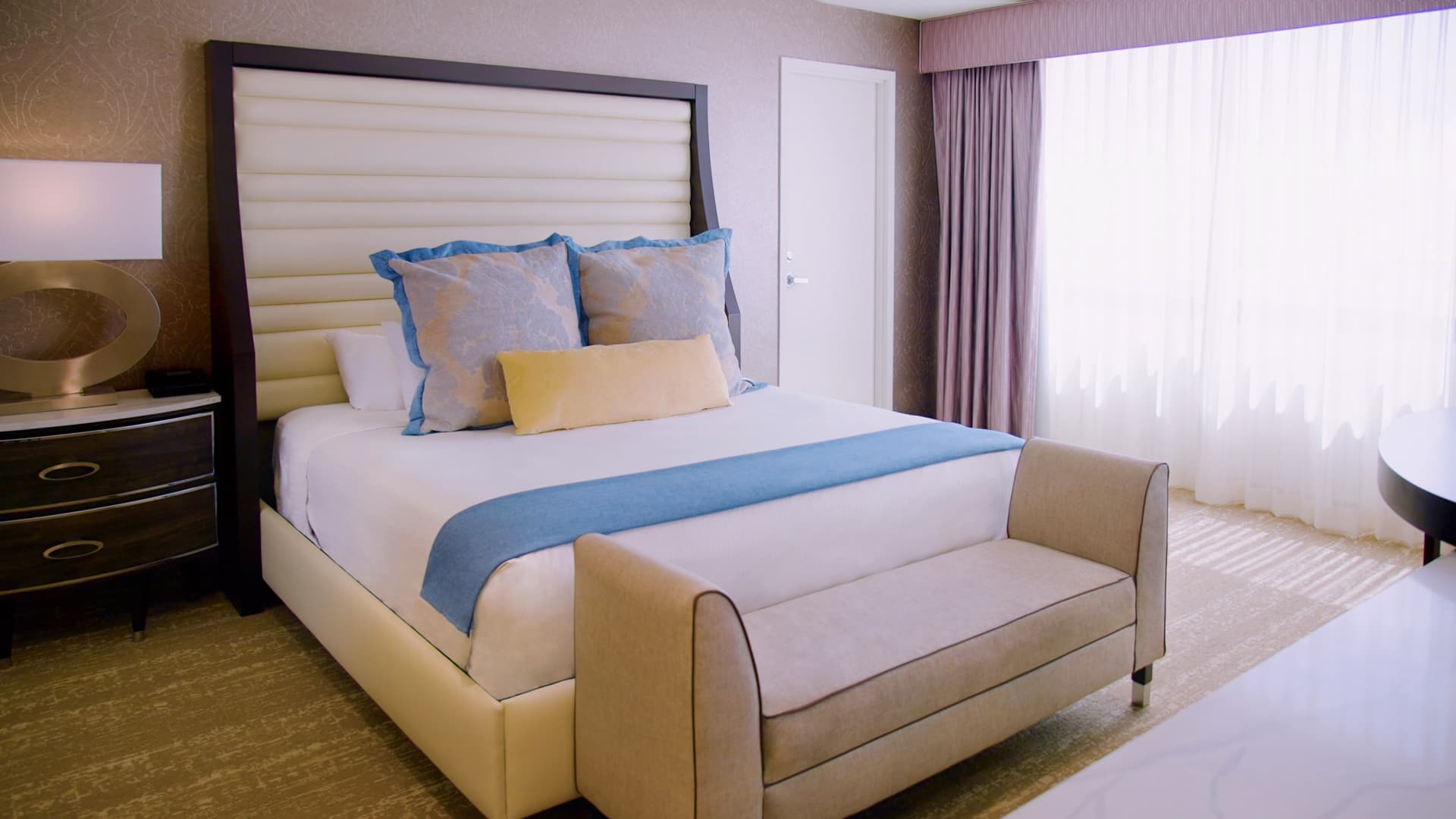 A hotel room with a large bed, nightstand, and window
