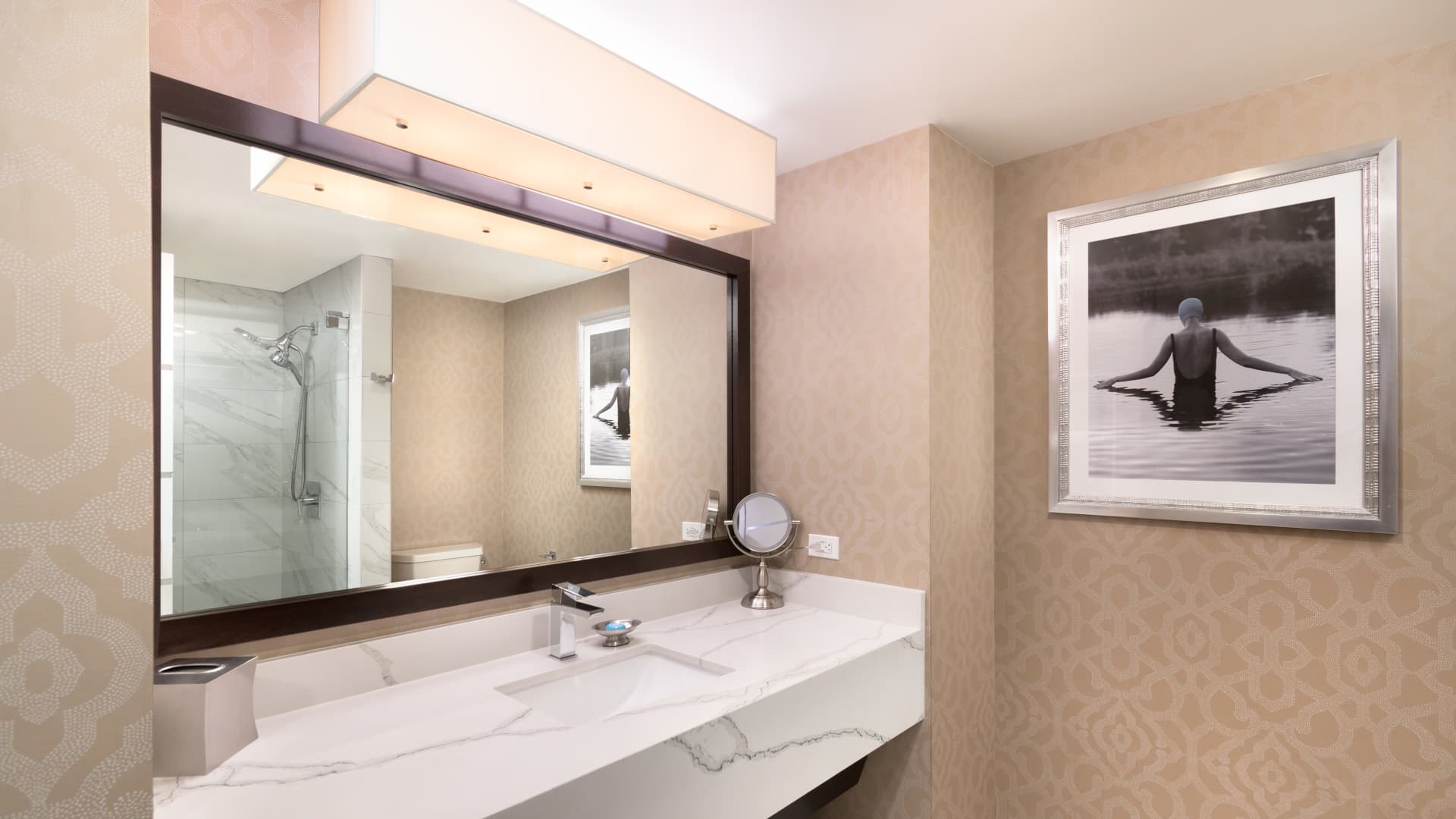 A bathroom with a large mirror, sink, and shower