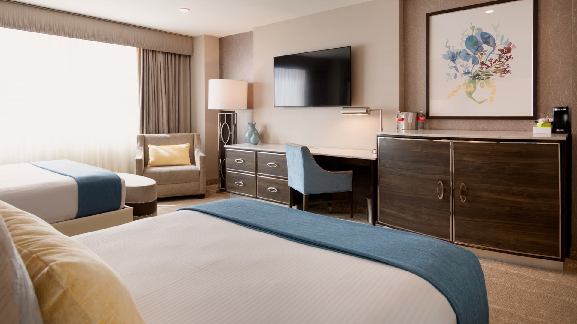 A hotel room with two queen beds, a desk, and a TV
