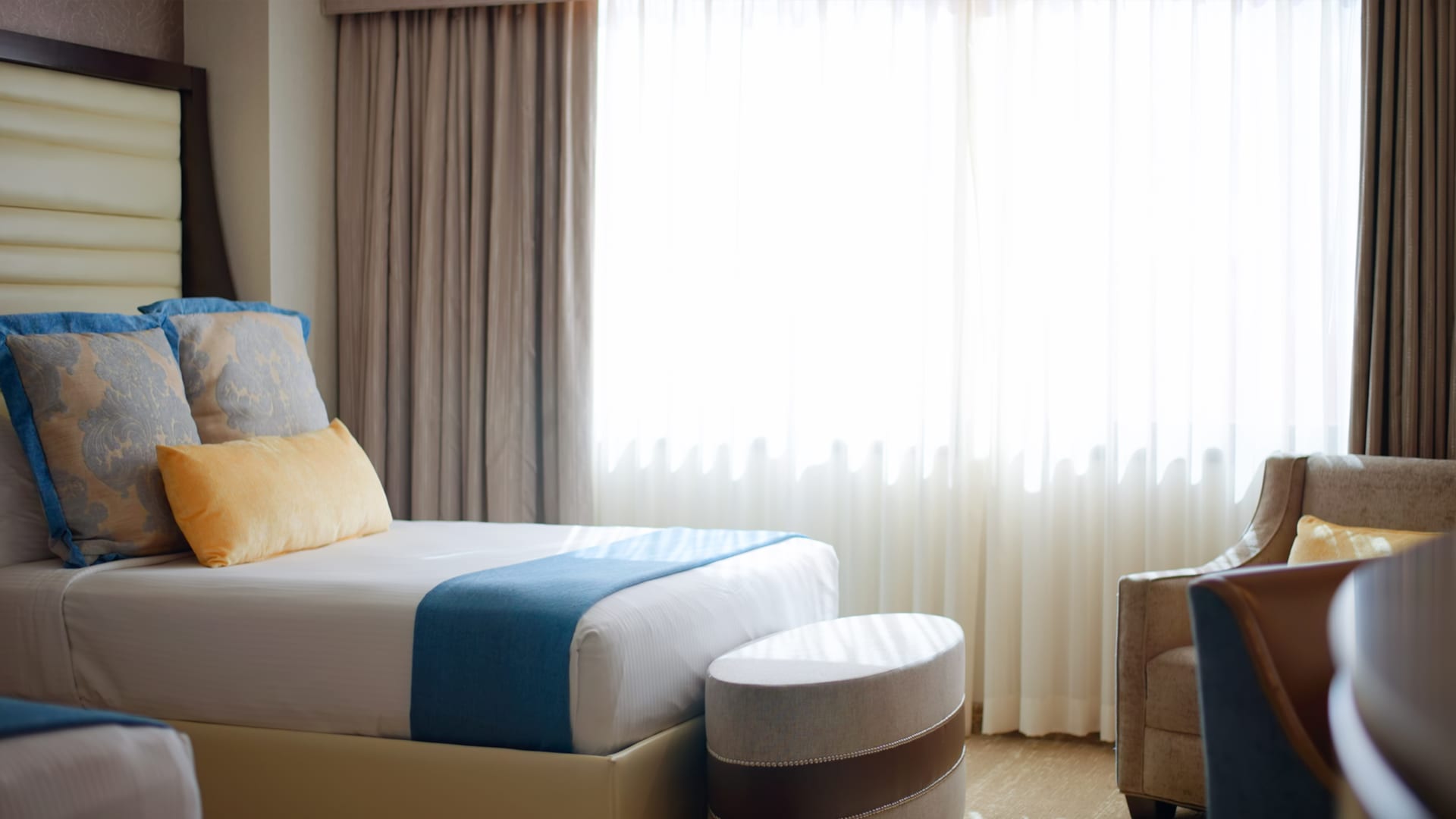 A hotel room with a bed, chair, and window