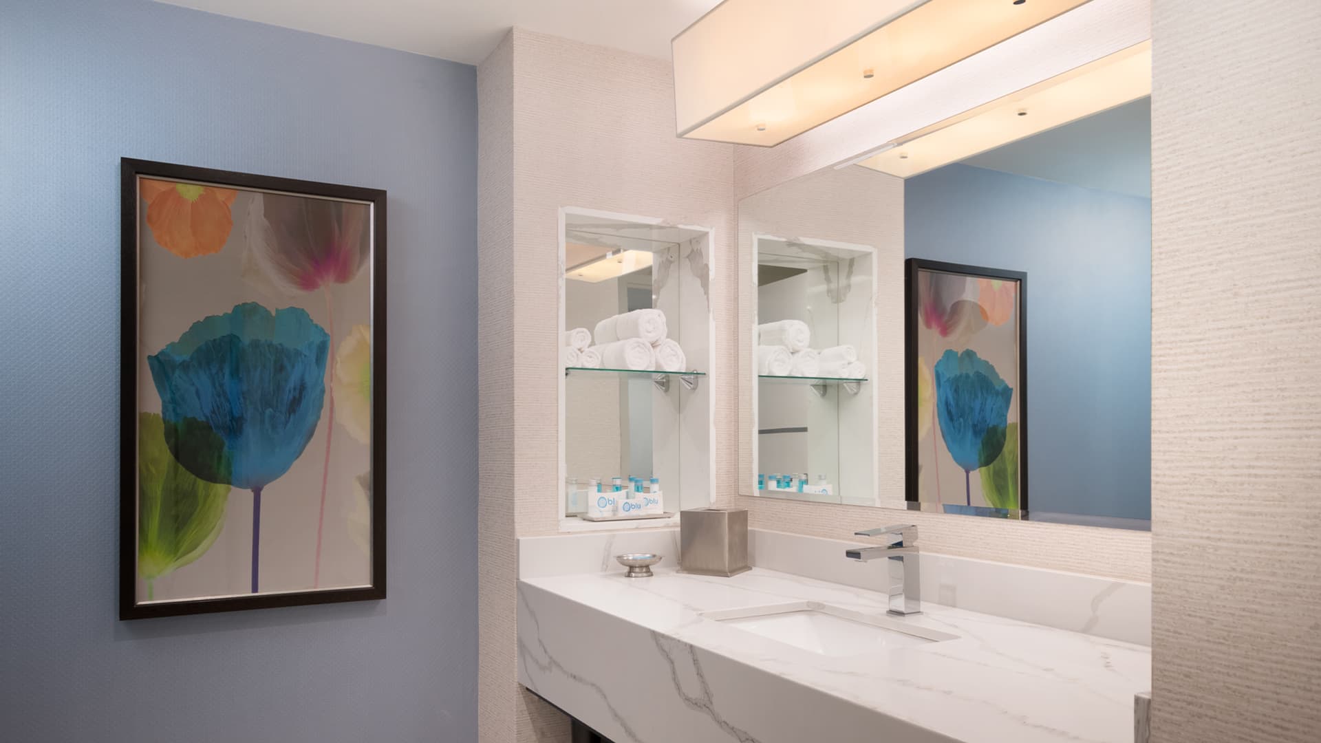 A bathroom vanity with a marble countertop, double sink, and mirror