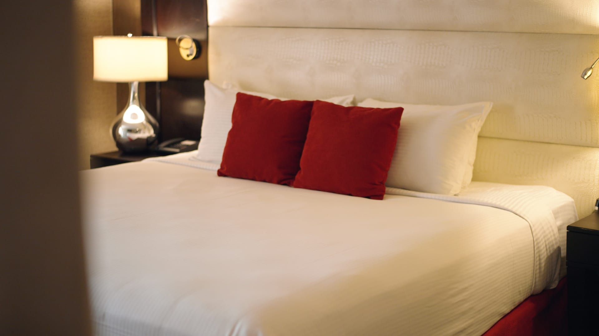 A neatly made bed with white sheets and red pillows