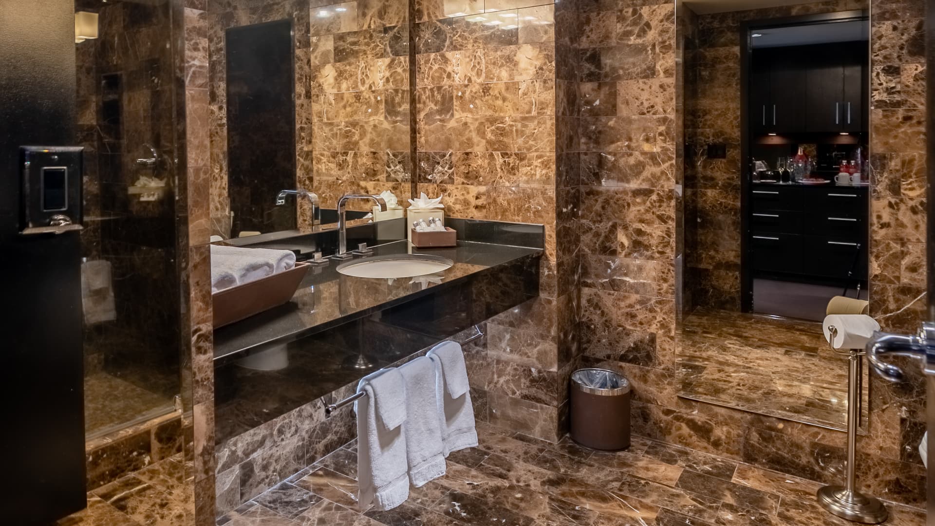 A luxurious bathroom with marble walls and a large mirror