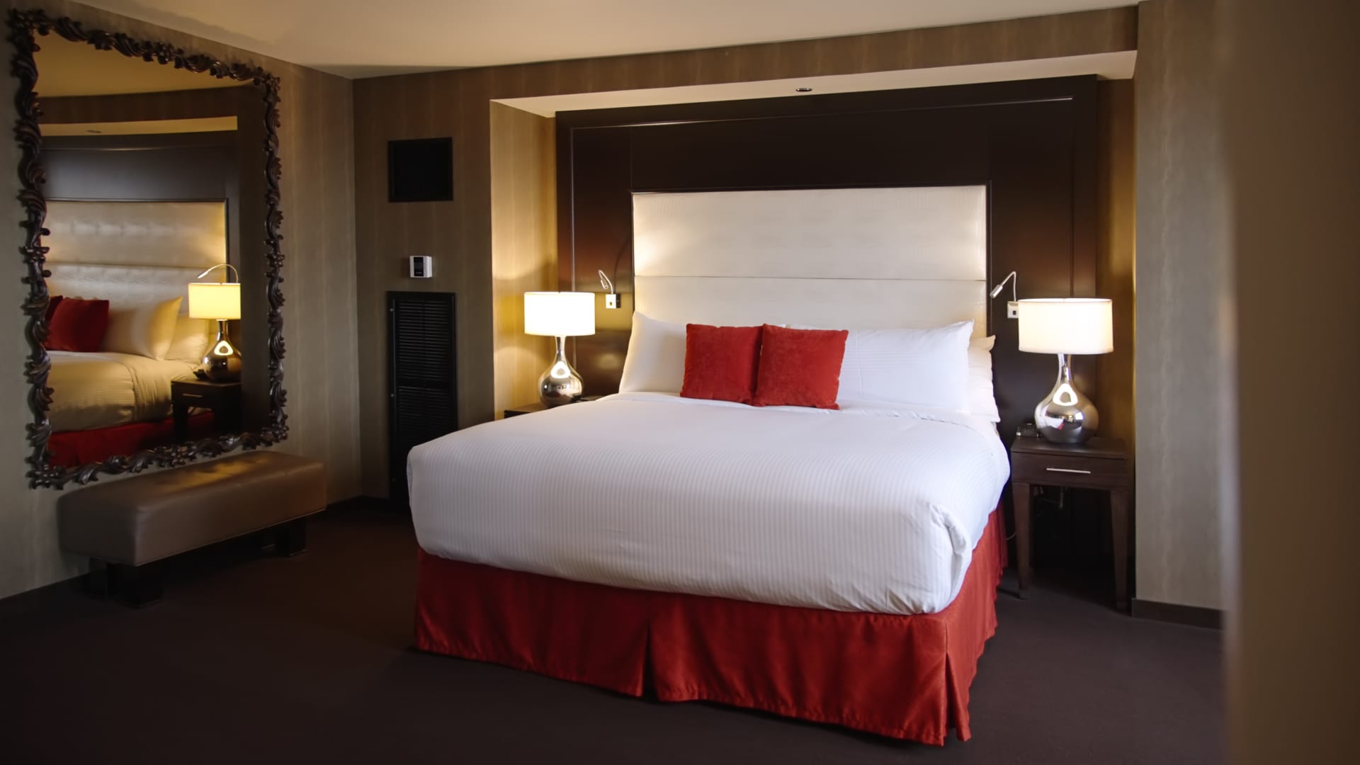 A hotel room with a large bed, two nightstands, and a mirror on the wall.
