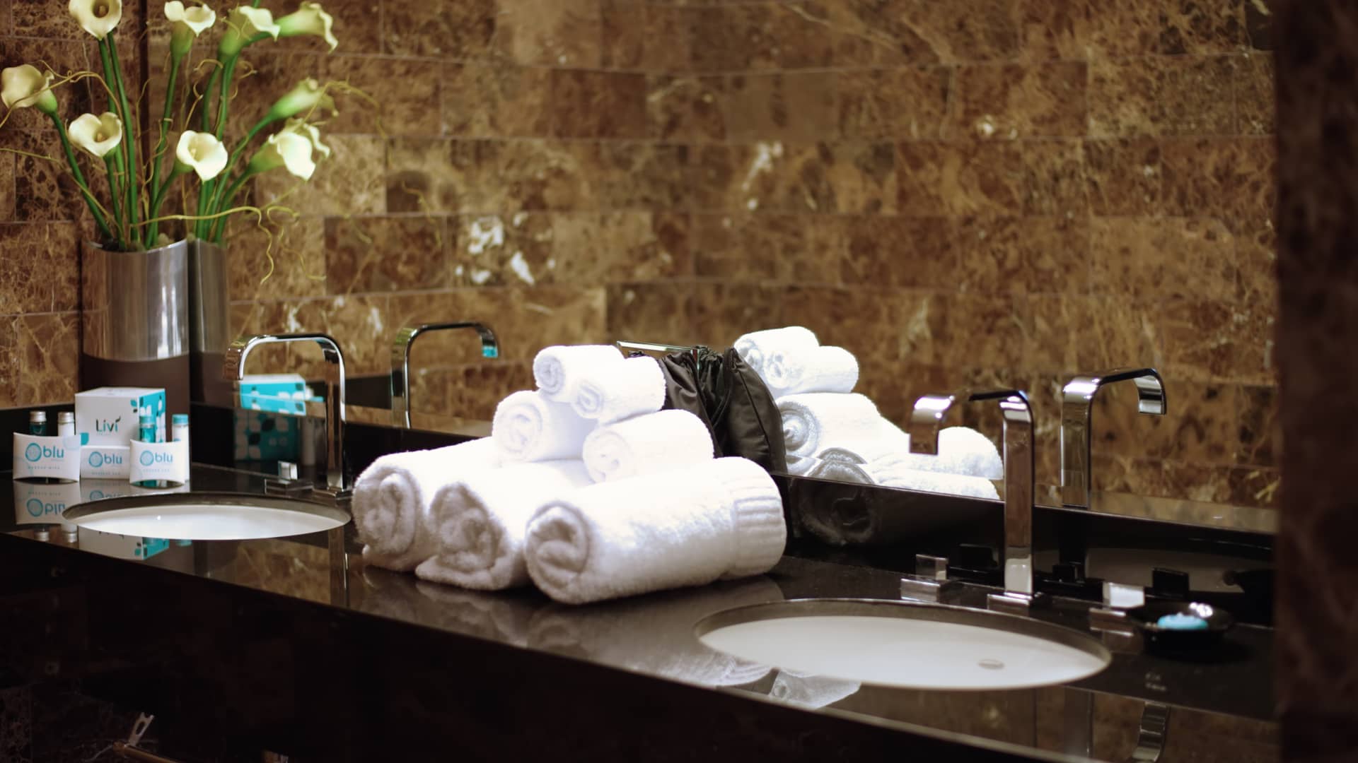 A bathroom vanity with two sinks, a mirror, and amenities.