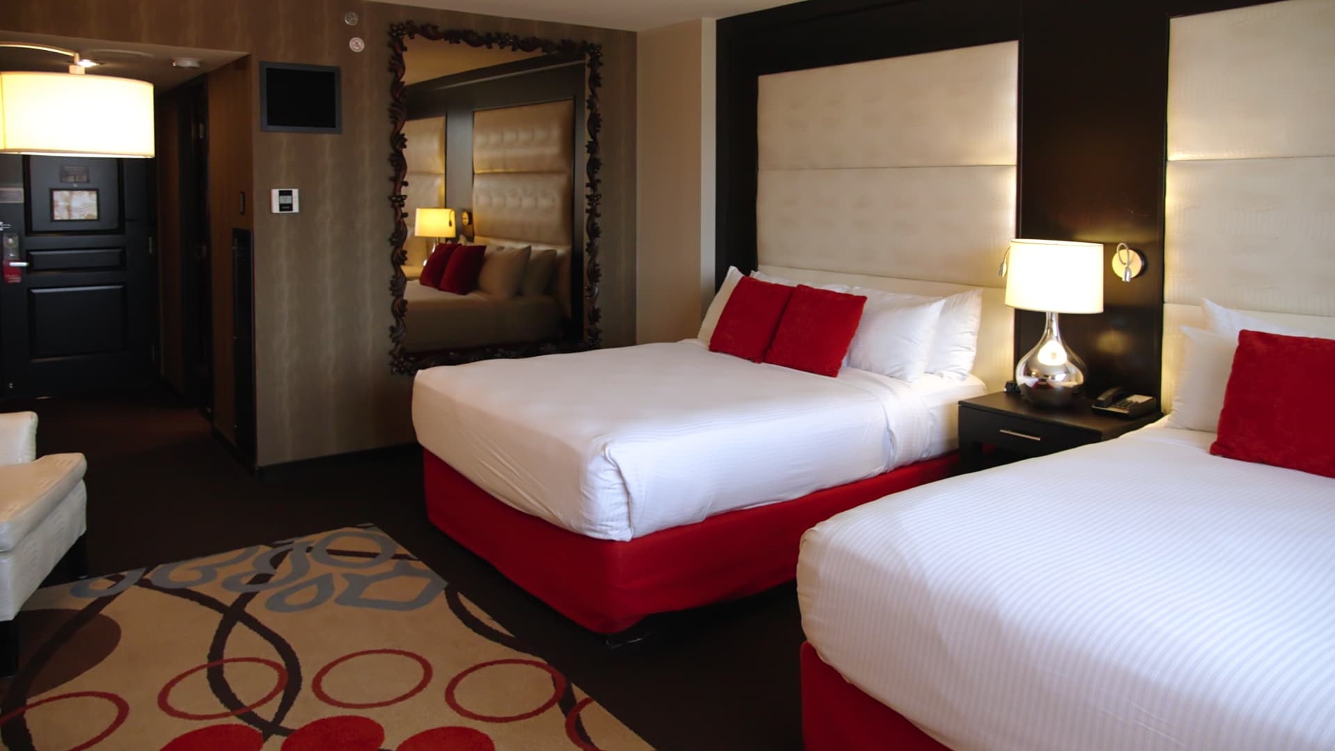A hotel room with two queen beds, a nightstand, and a mirror