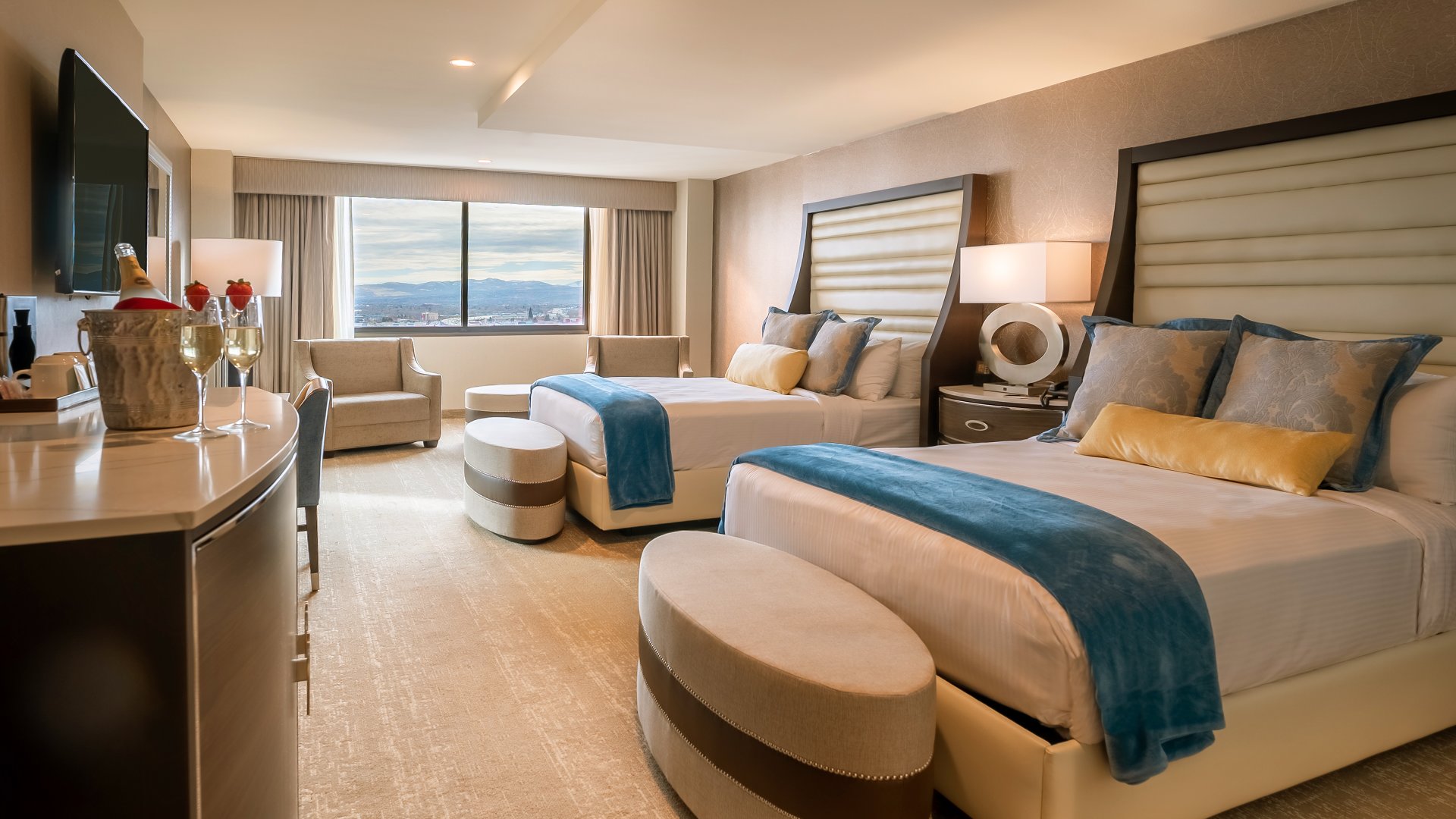 A luxurious hotel room with two beds, a sofa, and a window with a city view.