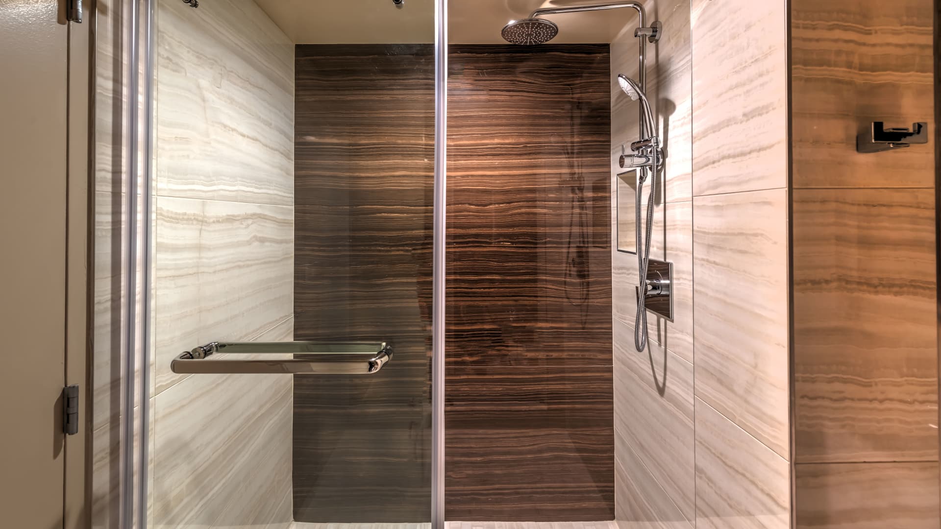 A modern shower with marble walls and a glass door