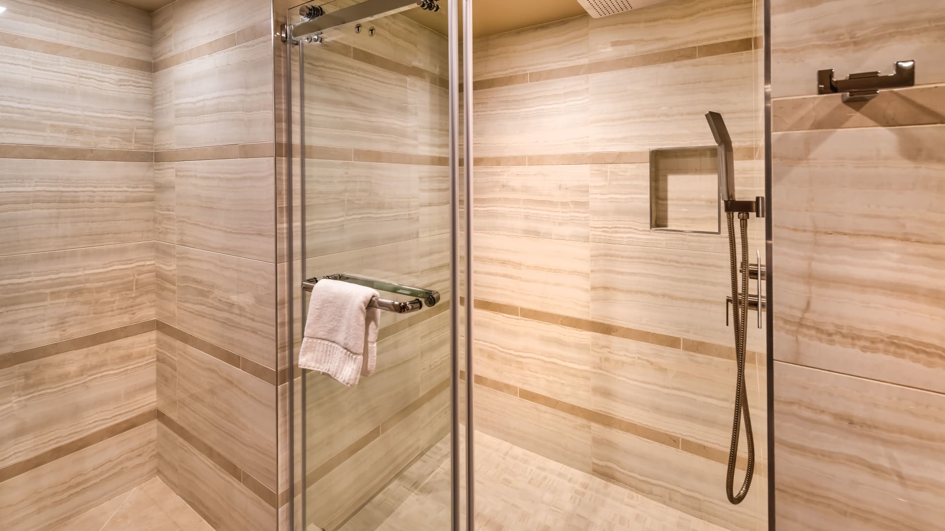 A luxurious shower with marble walls and a glass door