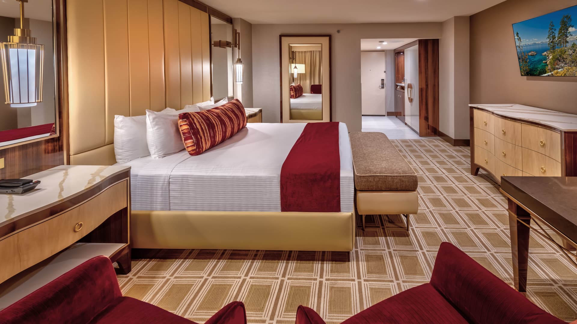 A wide view of a hotel room with a king-size bed, desk, dresser, and sofa.