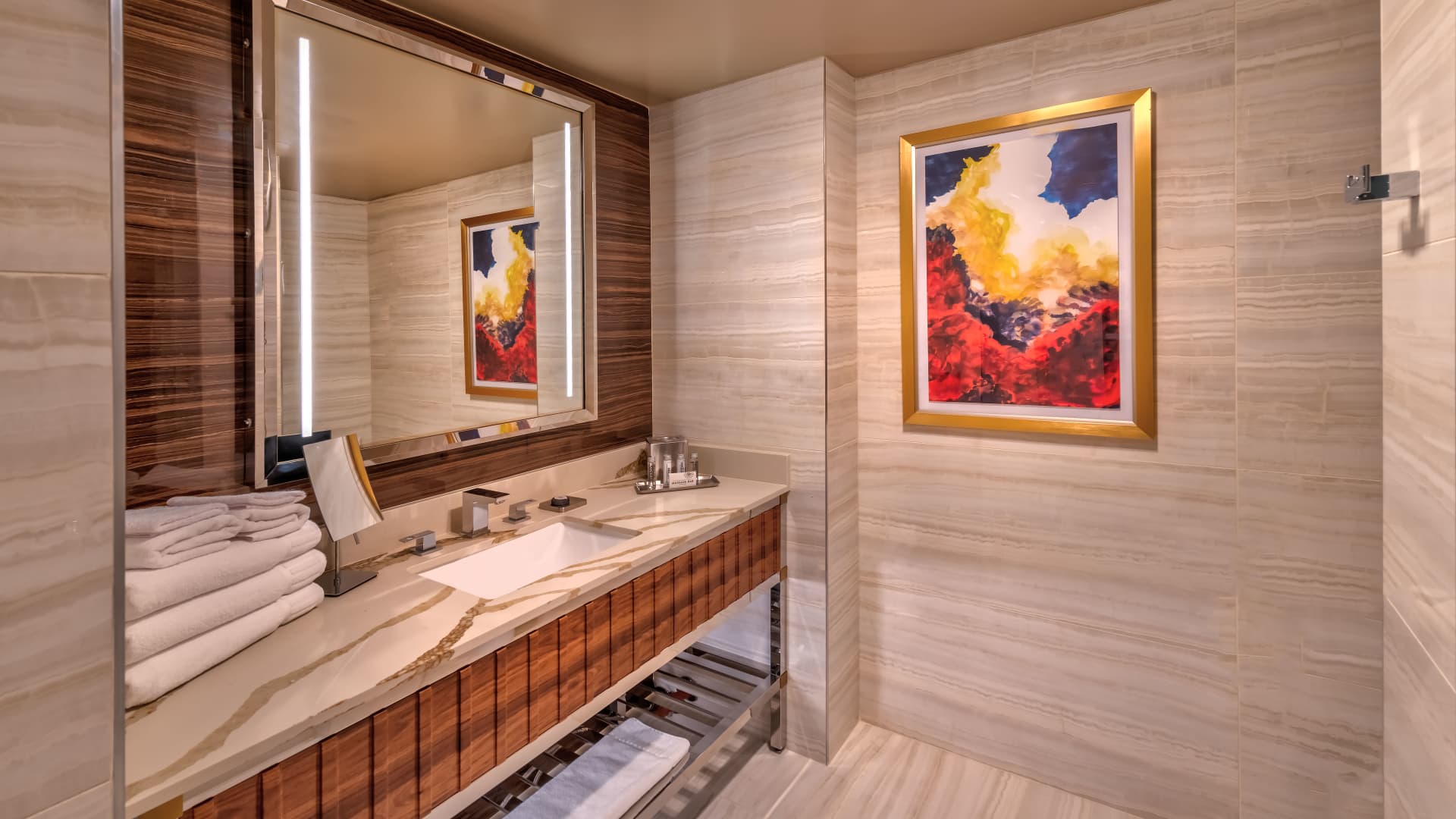 A bathroom with a marble countertop, wooden accents, and artwork.