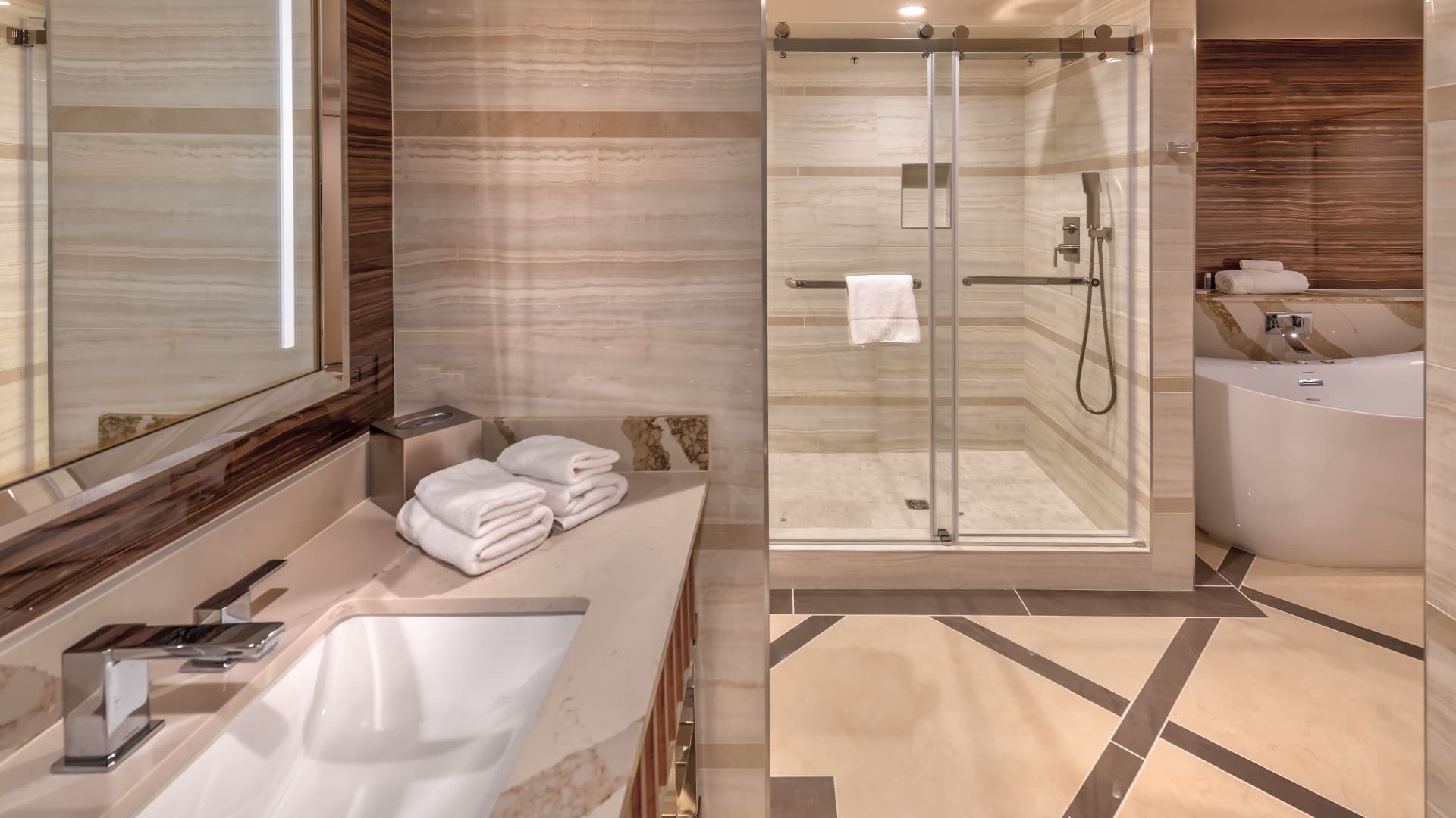 A luxurious bathroom with a marble countertop, glass-enclosed shower, and soaking tub.