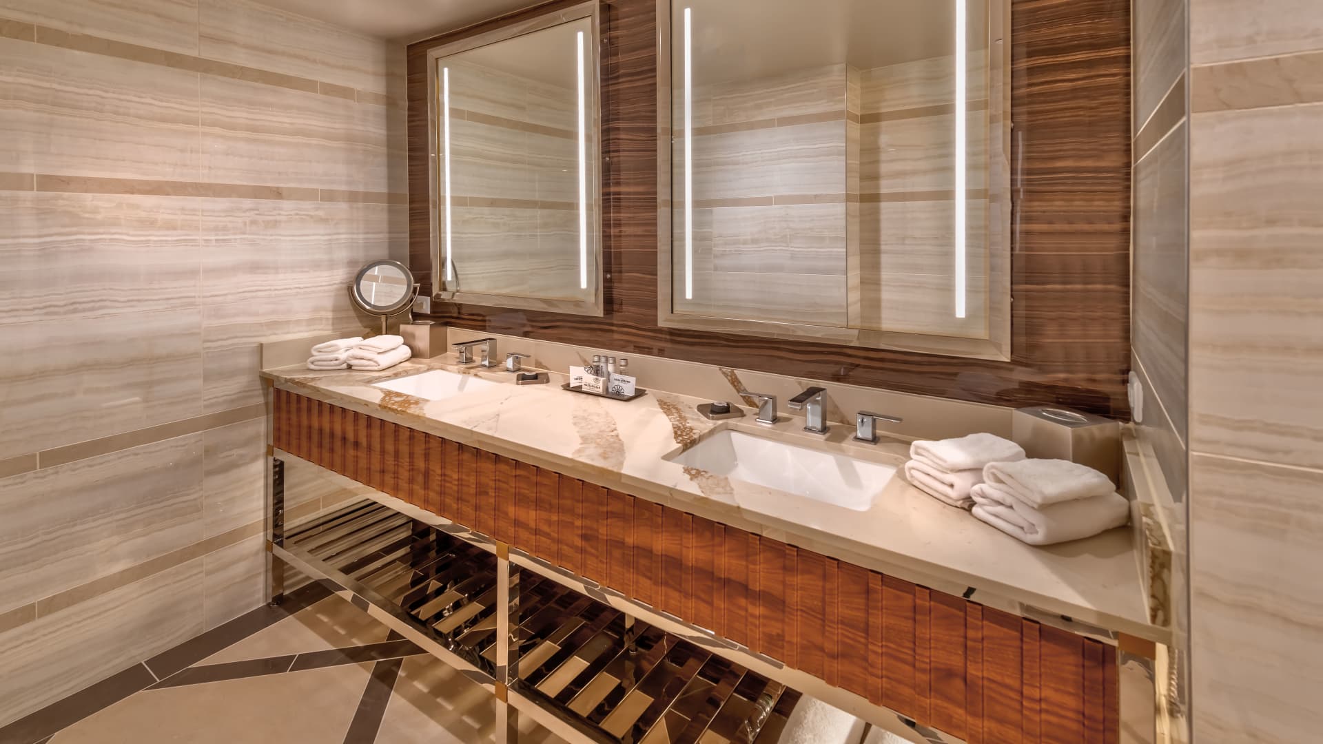 A luxurious bathroom with a double vanity, marble countertop, and wood accents.