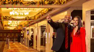 Couple admiring holiday decoration in hotel lobby.