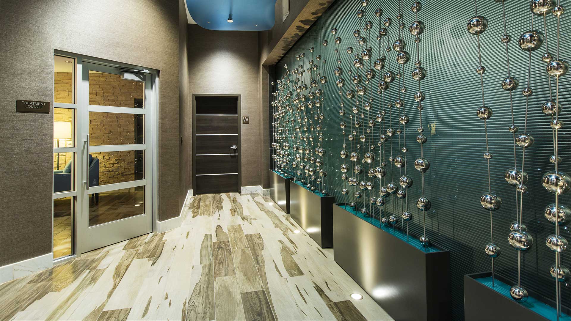 a lobby with a door, a wall with a unique art installation, and a ceiling