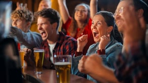 Photo of friends at bar watching and cheering for sports event.